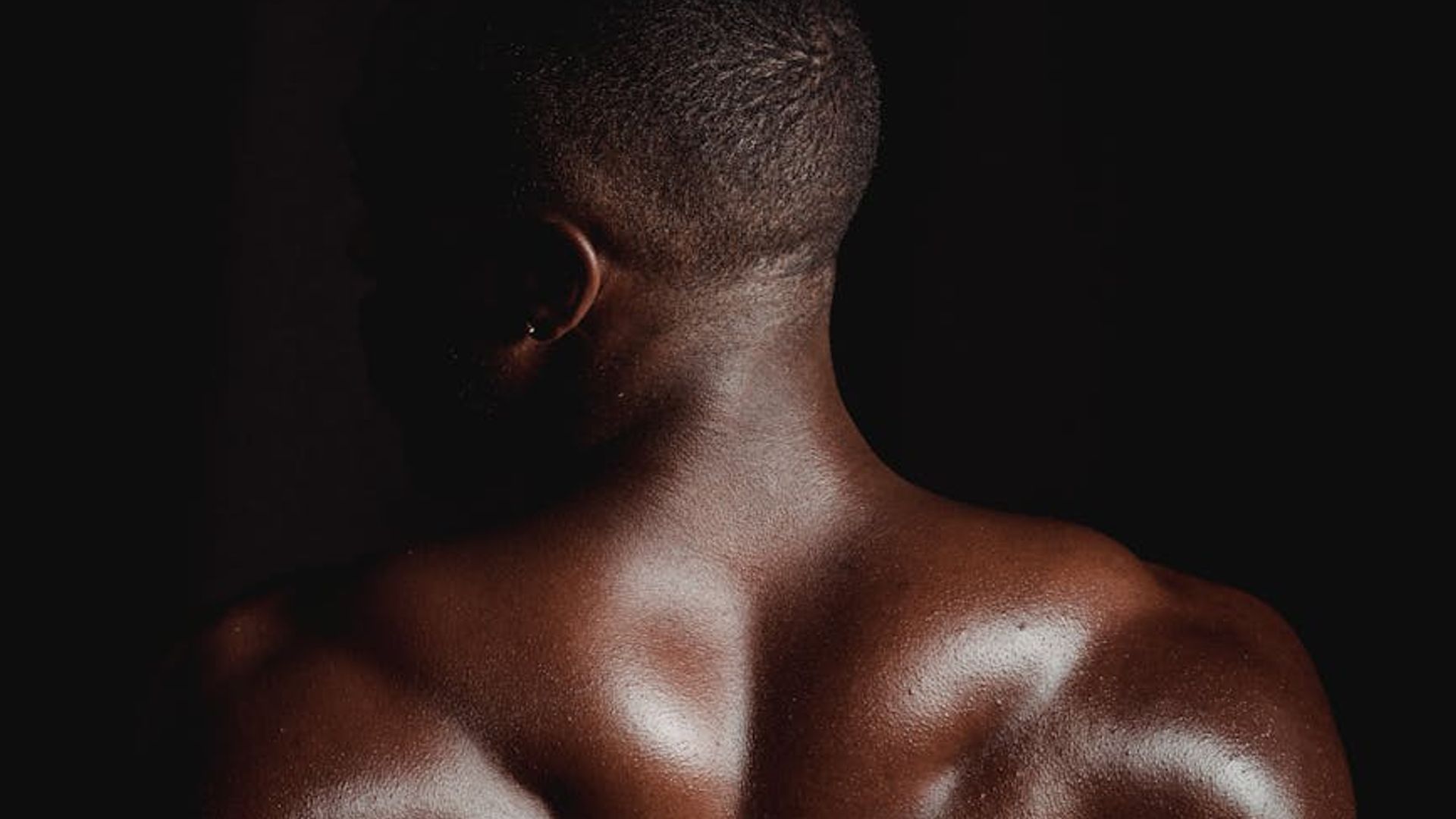Strong man exercising core muscles in dark gym environment.